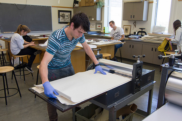 A student in Sister Jimison's Printmaking class, prepares to use the press for an assignment.