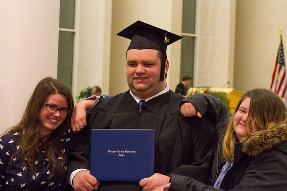 A graduate poses with his family after Convocation in the Taylor Chapel.]