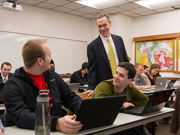 Brother Clark, professor of Productions and Operations Management smiles as he helps his students understand The Root Beer Game.