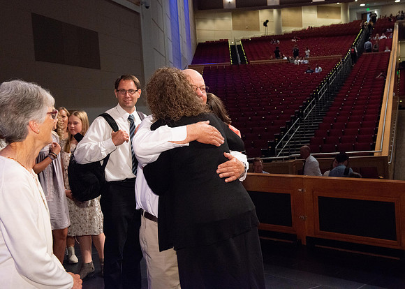 Sister Heather Hall huging her family after devotional.