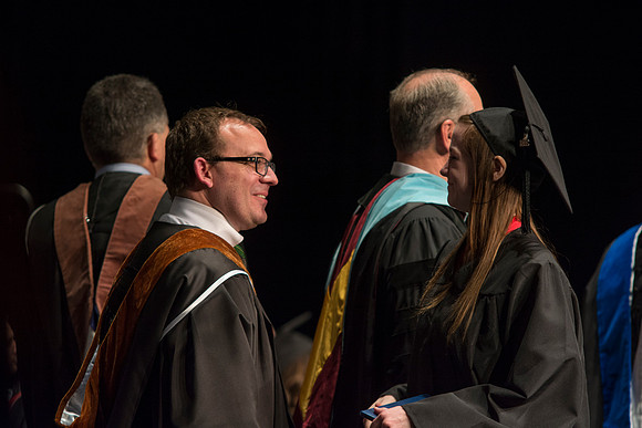 Faculty members hand degrees to and congratualate graduates of the College of Performing and Visual Arts.