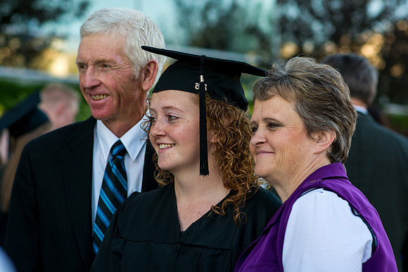 A graduate stands with her grandparents.