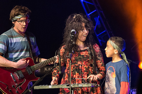 A local kid, Justin, performs with his music teacher, Emma Huntington and her band, The Locals, the Big Rock Show.