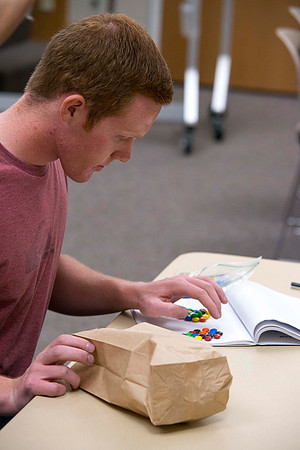 A Political Science student in Brother Adamson's class counts out the number of M&amp;M's he should have before the activity starts.