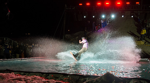 Students make a run down a snowy slope and across a pond of water in the annual event of Pond Skimming.