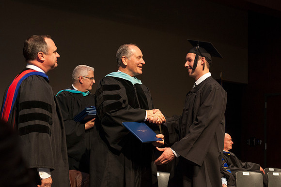 A graduate from BYU-Idaho shakes hands with Ric Page, Associate Academic Vice President from Support Services, during convocation of the College of Language and Letters in the Manwaring Center. Photo