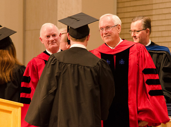Elder Robert C. Gay and President Kim B. Clark congratulate a student. Photo by Erik Hill.