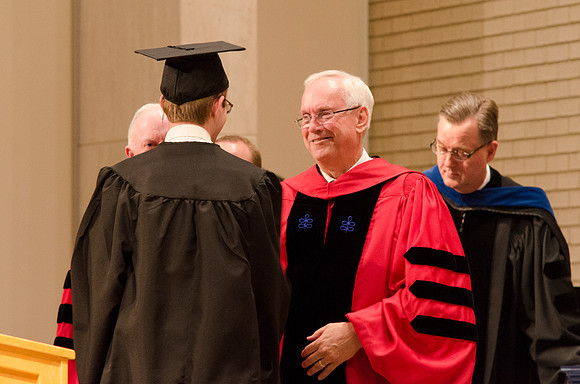 Elder Robert C. Gay of the first Quorum of the Seventy congratulates and shakes the hand of a Graduate. Photo by Erik Hill.