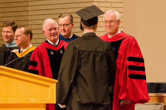 Elder Robert C. Gay and President Kim B. Clark congratulate a student. Photo by Erik Hill.