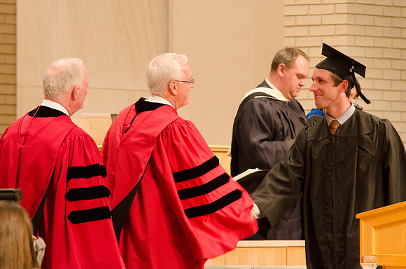 Elder Robert C. Gay and President Kim B. Clark congratulate a student. Photo by Erik Hill.
