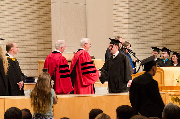 Elder Robert C. Gay and President Kim B. Clark congratulate a student. Photo by Erik Hill.