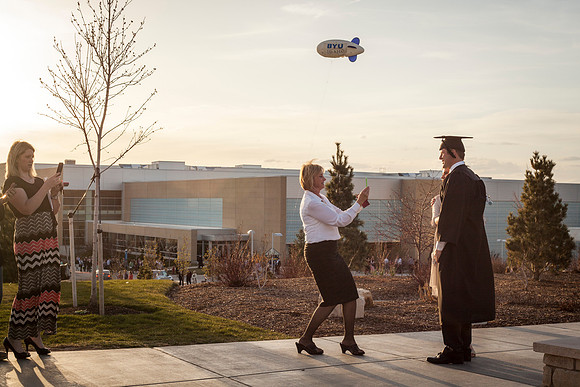 A graduate from BYU-Idaho gets his picture taken outside the Taylor Building.