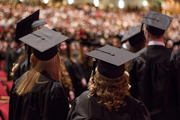 Students look off into the distance at friends and family that have gathered to see the 2014 Winter Semester Graduation at Commencement in the i-Center.
