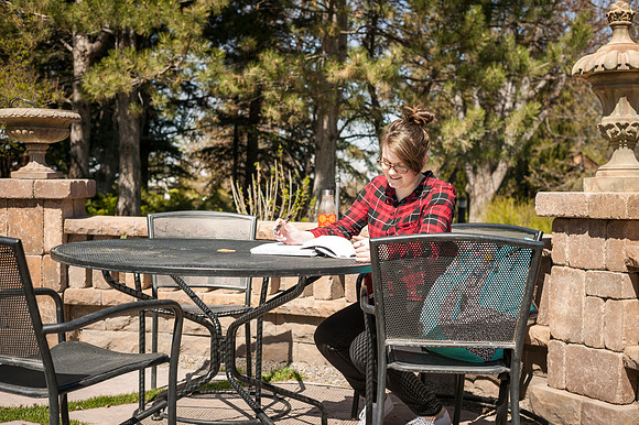 An student majoring in English, looks over her books in the gardens.