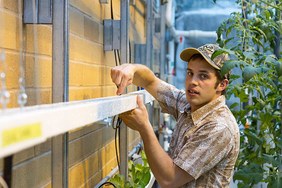 Justin Hatch, manager of the Plant &amp; Soil Science Green House, works during finals week in the Benson Building.