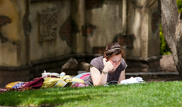 Student Michelle Crossan studys on the grass in the gardens on campus