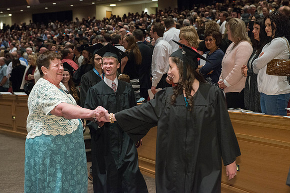 Students are greeted by a friend in the staff, as they walk in the processional. Photo by Ryan Chase