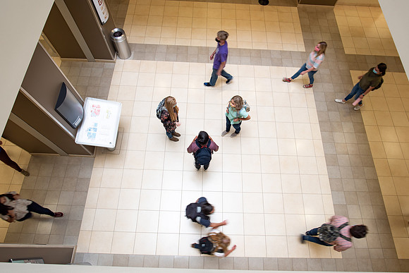 Examples of students staying safe and healthy during the COVID-19 pandemic by social distancing, following pathway arrows, and wearing face masks.