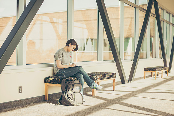 Paige Davis studys in the sky bridge that connects the Manwaring Center and library.