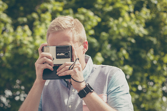 Tyler Rickenbach, a University Relations Photographer, takes a picture with an old disc camera.