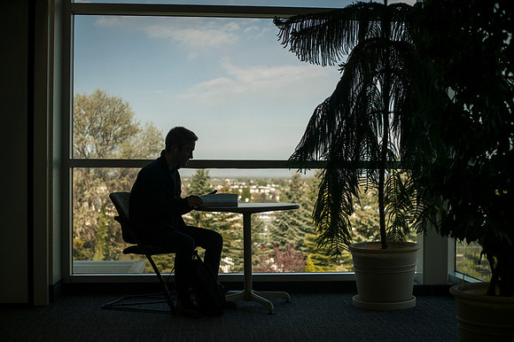 A student flips through his textbook as the sun rises over campus.