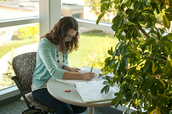 A student study in the Ricks Building as the sun starts to cast its light on campus.