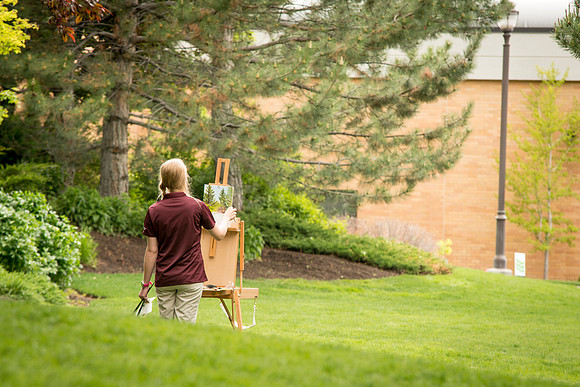 A student from the Art Department paints a landscape in the gardens one afternoon.