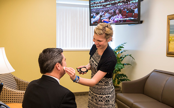 Behind the scenes of devotional, the speaker, Drew Eader, gets a little powder to reduce the shine from the bright lights.