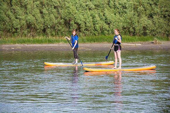Students of Brigham Young University-Idaho go standup paddle boarding on the river at Warm Slough.