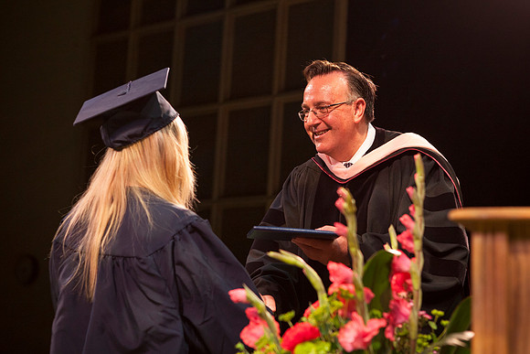 Jon Linford shakes hands with graduates as they are handed their diplomas during Convocation held in the Kirkham Building. Photo by Tyler Rickenbach