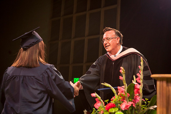 Jon Linford shakes hands with graduates as they are handed their diplomas during Convocation held in the Kirkham Building. Photo by Tyler Rickenbach
