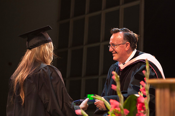 Jon Linford shakes hands with graduates as they are handed their diplomas during Convocation held in the Kirkham Building. Photo by Tyler Rickenbach