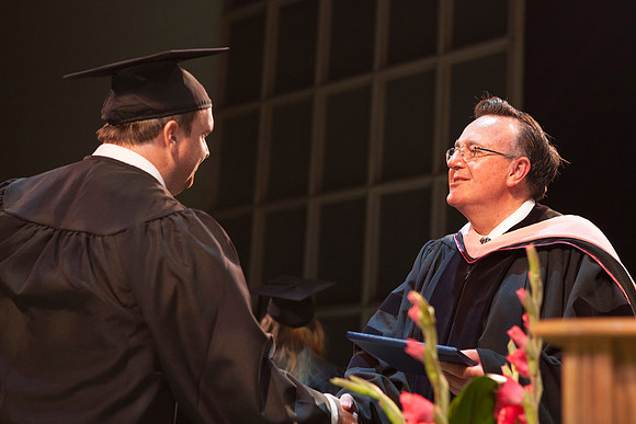 Jon Linford shakes hands with graduates as they are handed their diplomas during Convocation held in the Kirkham Building. Photo by Tyler Rickenbach