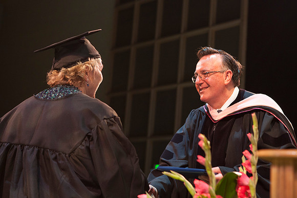 Jon Linford shakes hands with graduates as they are handed their diplomas during Convocation held in the Kirkham Building. Photo by Tyler Rickenbach