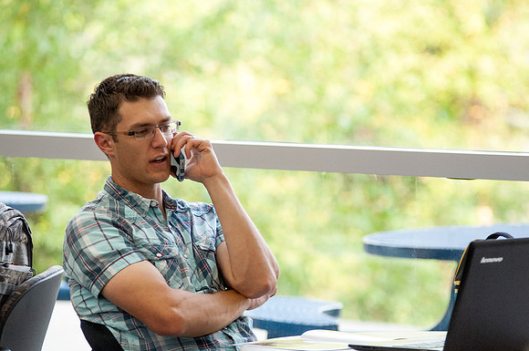 A student talks on the phone in between classes in the Ricks Building.