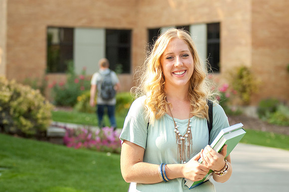 A freshman walks to class with books in hand.