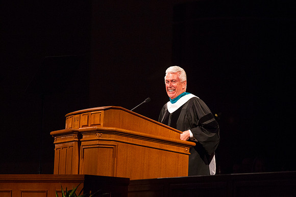 President Dieter F. Uchtdorf smiles as his wife sits down after helping fix his robe.
