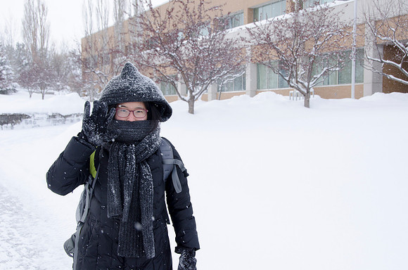 A student dressed in winter gear outside the Spencer W. Kimball Student and Administrative Services Building.