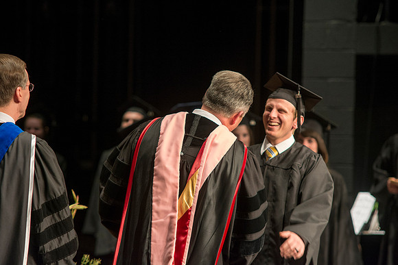 Faculty members hand degrees to and congratualate graduates of the College of Performing and Visual Arts.