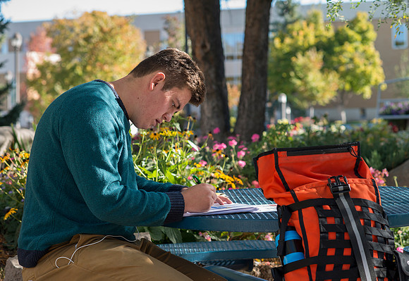 A student takes advantage of the beautiful fall weather to do his studies outside the Romney Building.