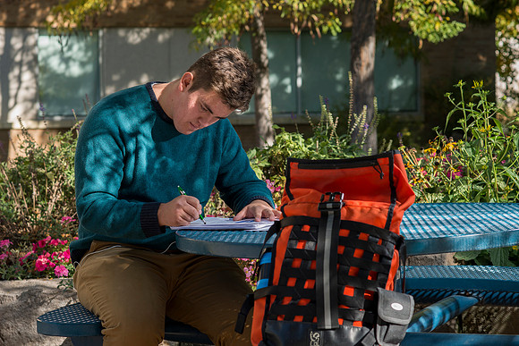 A student takes advantage of the beautiful fall weather to do his studies outside the Romney Building.