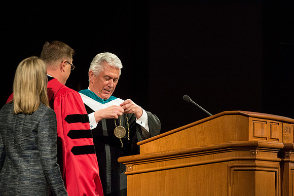 President Uchtdorf presents Clark G. Gilbert with his medallion. Sister Gilbert helps fasten it.