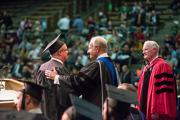 Elder W. Craig Zwick and President Kim B. Clark award diploma covers to graduates in the College of Business and Communication.