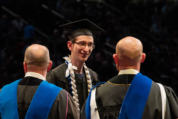 Students graduate and walk to receive their diplomas during convocation in the College of Physical Sciences and Engineering.
