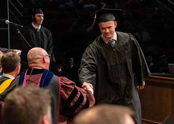Students graduate and walk to receive their diplomas during convocation in the College of Physical Sciences and Engineering.