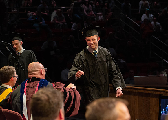 Students graduate and walk to receive their diplomas during convocation in the College of Physical Sciences and Engineering.
