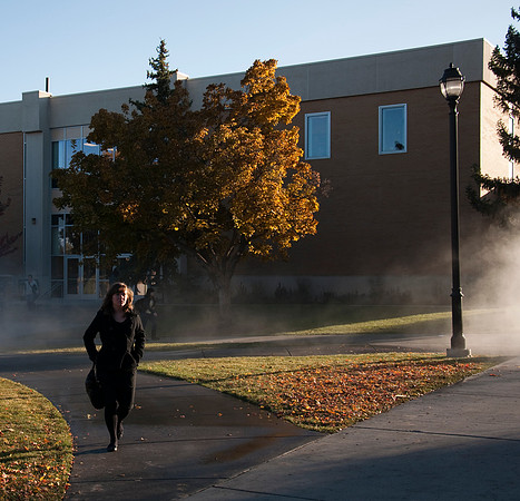 Students walk to class while campus grounds workers airing out sprinkler systems.