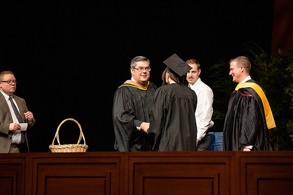 Students graduate and walk to recieve their diplomas during convocation in the College of Business and Communications.