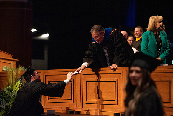 Students graduate and walk to recieve their diplomas during convocation in the College of Business and Communications.
