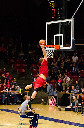 A student leaps over a school desk to dunk the ball.